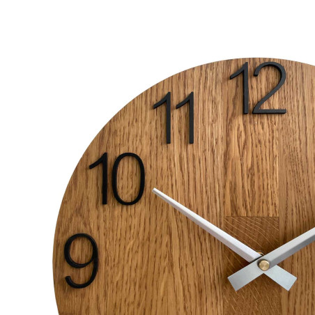 Drewniany zegar o symetrycznym kształcie i wycięciu inspirowanym motywami natury.