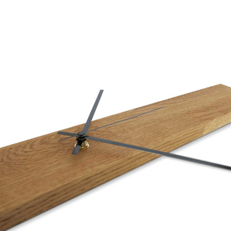 Minimalistyczny drewniany zegar w kształcie wąskiego panelu ze srebrnymi i czarnymi wskazówkami. Minimalistyczny drewniany zegar w kształcie wąskiego panelu ze srebrnymi i czarnymi wskazówkami.